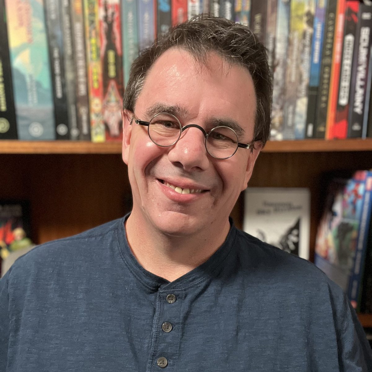 Wes Allen in front of his TTRPG book shelf.